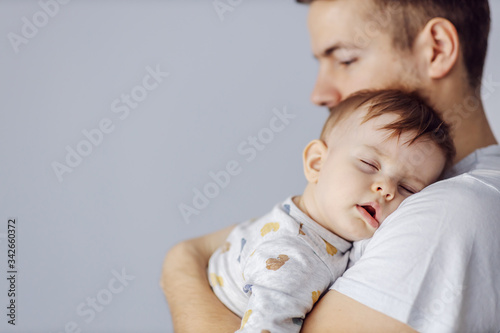 Closeup of adorable little boy sleeping deeply and dreaming while his caring father holding him.