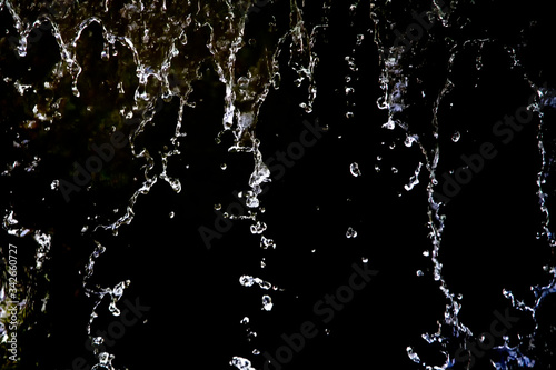 Close up of the water drop on black background. Movement of the drop water.White liquid is driping onto the black background.