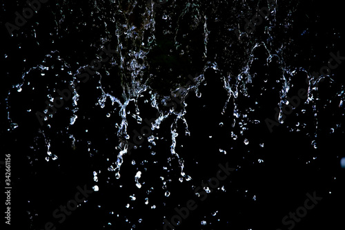Close up of the water drop on black background. Movement of the drop water.White liquid is driping onto the black background.