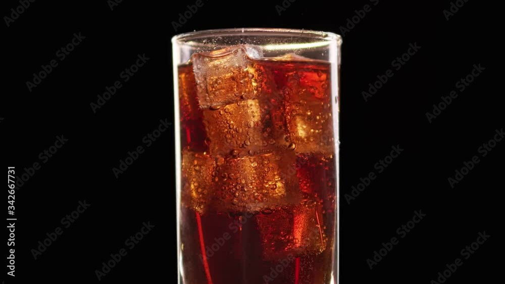 Refreshing cola beverage with rising up air bubbles in transparent glass. Medium shot on RED camera