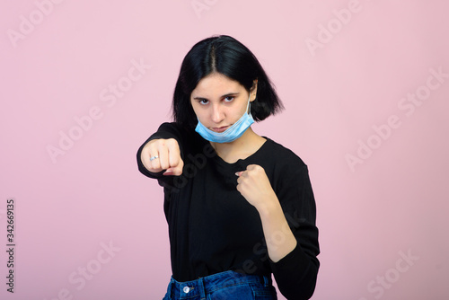 The caucasian girl in blue colored protective face mask. The girl looking at camera. Portrait shot over pink background. virus and pollution protection concept.