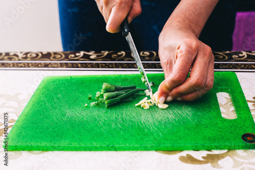 Cuts onions on a green board