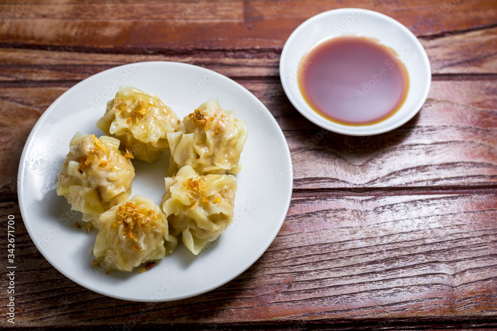 Chinese Steamed Dumpling, Shumai on white dish served with soy sauce on wooden table. Delicious Dimsum pork. Chinese Steamed Dumpling, Shumai on white dish served with soy sauce on wooden table. Delicious Dimsum pork.