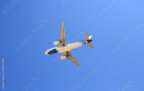 Airplane flying under blue sky. Seen from below.