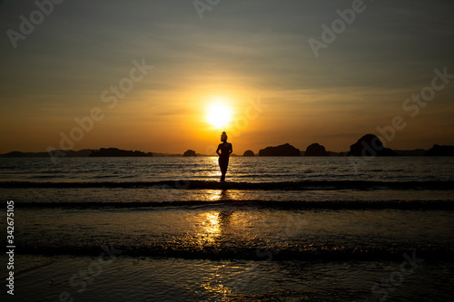 Silhouette of a girl on the beach, against the backdrop of the sea and sunset