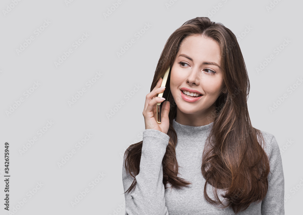 Young business woman talking on mobile phone. Smiling student girl using smartphone. Isolated on gray background studio shot, copy space Young business woman talking on mobile phone. Smiling student girl using smartphone. Isolated on gray background studio shot, copy space