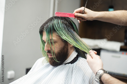  Hairdresser combing long hair of male customer before providing a haircut at barber shop