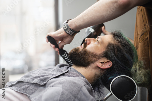  Barber styling a beard of male customer at barber shop