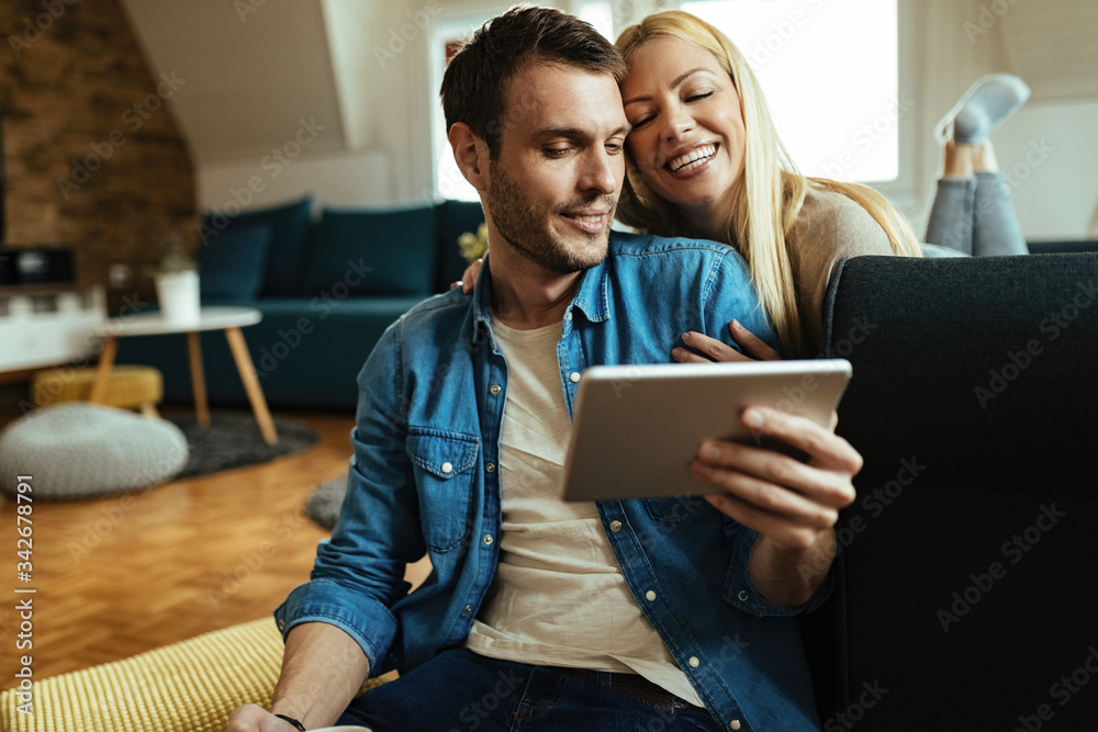 Loving couple using touchpad while relaxing in the living room.