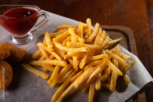 Nuggets french fries and sauce on a dark wooden background