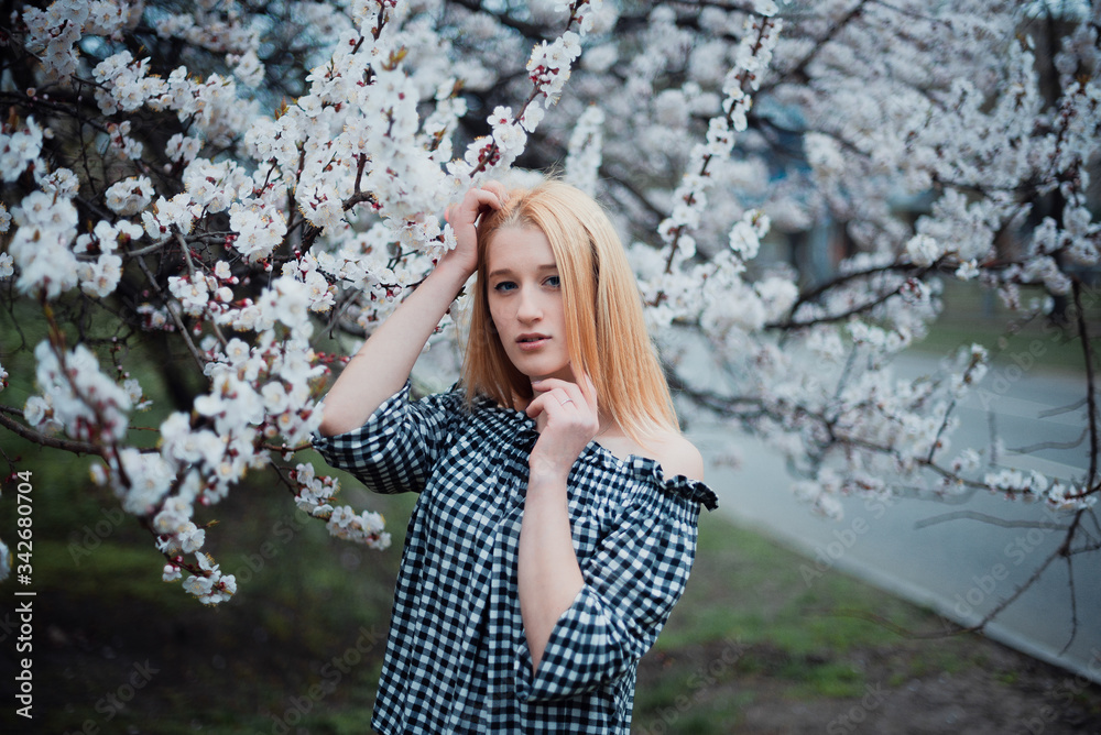 Beautiful young blonde girl on a background of flowering trees Beautiful young blonde girl on a background of flowering trees
