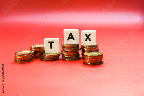 STacks of coins with tax lettering on top isolated on a red background,  Business and tax management concept