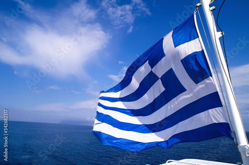 Greece, Aegean sea, Cyclades islands, travelling to Mykonos, Greek flag waving on a ferry boat.
