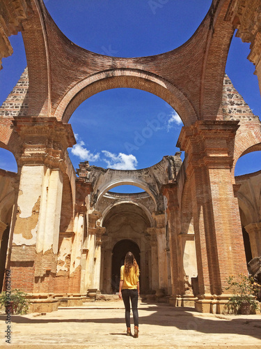 Mujer camina hacia el altar de las ruinas de la catedral de Antigua Guatemala, entre columnas reconstruidas