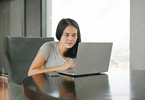 Asian woman using laptop computer working online at home. People during the introvert time at home from the epidemic © zilvergolf