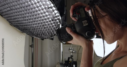 Female photographer taking product photos in home studio - close up on side profile