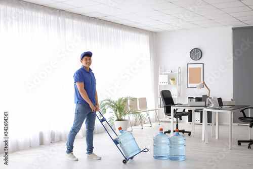 Delivery man with bottles of water in office