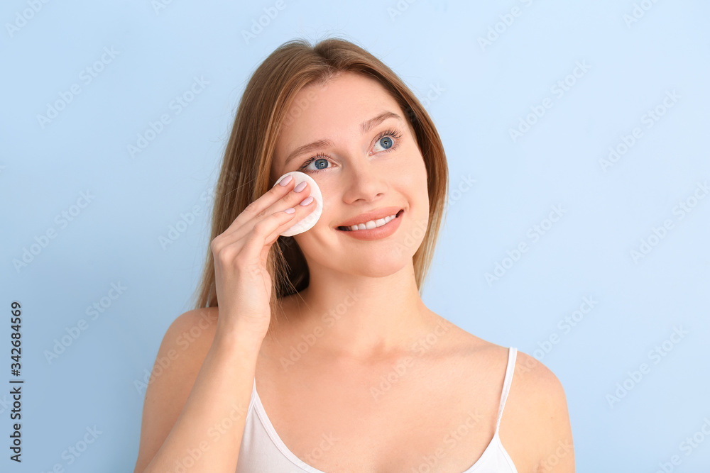 Beautiful young woman with cotton pad on color background Beautiful young woman with cotton pad on color background