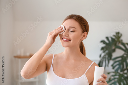 Foto Beautiful young woman removing makeup at home