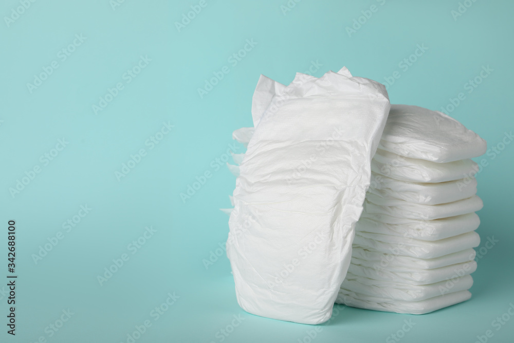 Stack of diapers on light blue background. Space for text - obrazy, fototapety, plakaty 