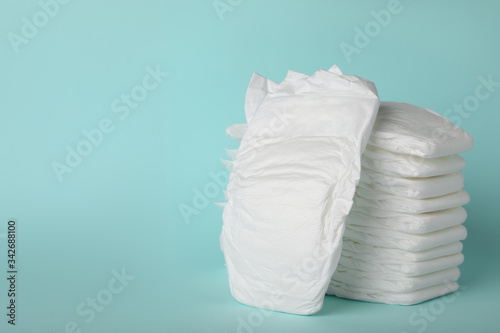 Stack of diapers on light blue background. Space for text photo