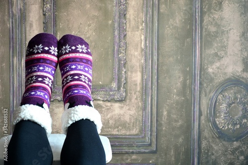rest at home in woolen warm pattern sheepskin socks , legs up , wooden vintage carved interior 