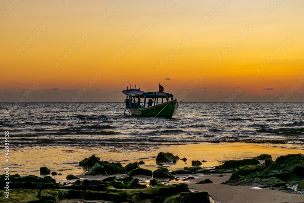 Obraz premium A boat in the sea with the sunset background at Koh Ta Kiev, Cambodia