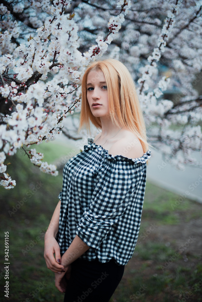 Beautiful young blonde girl on a background of flowering trees Beautiful young blonde girl on a background of flowering trees