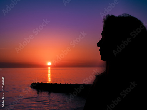 The silhouette of a girl against the backdrop of a beautiful sea sunset