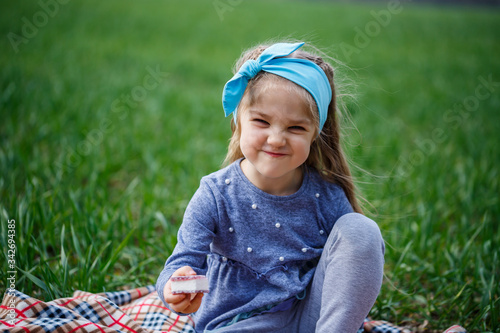 Canvas Print little girl child sits on the bedspread and eats cookies and marmalade, green gr