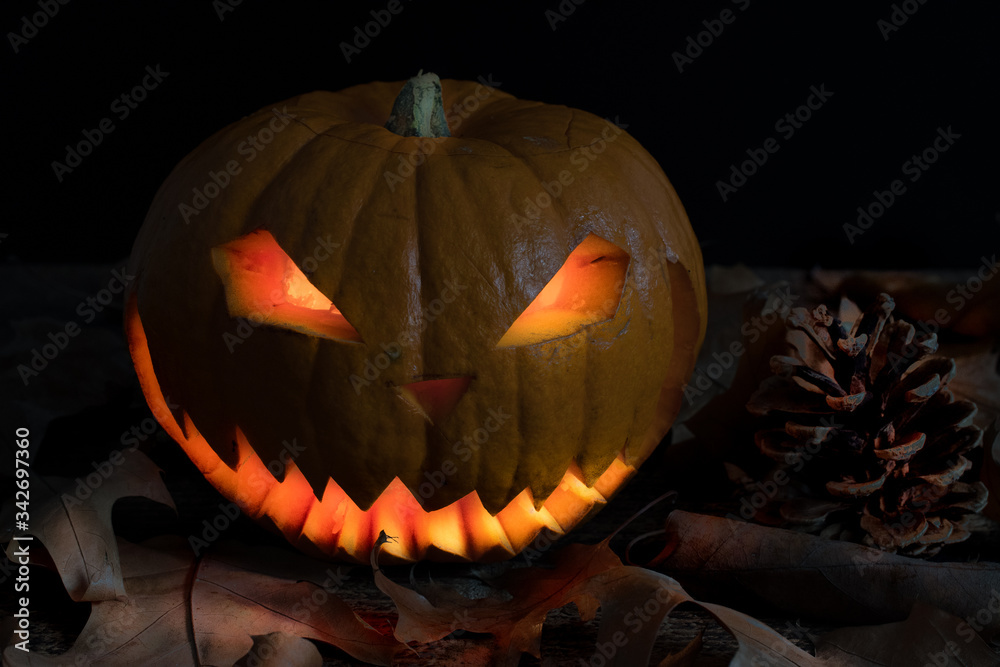 Fototapeta premium Scary and spooky hand carved Halloween pumpkin with flames inside