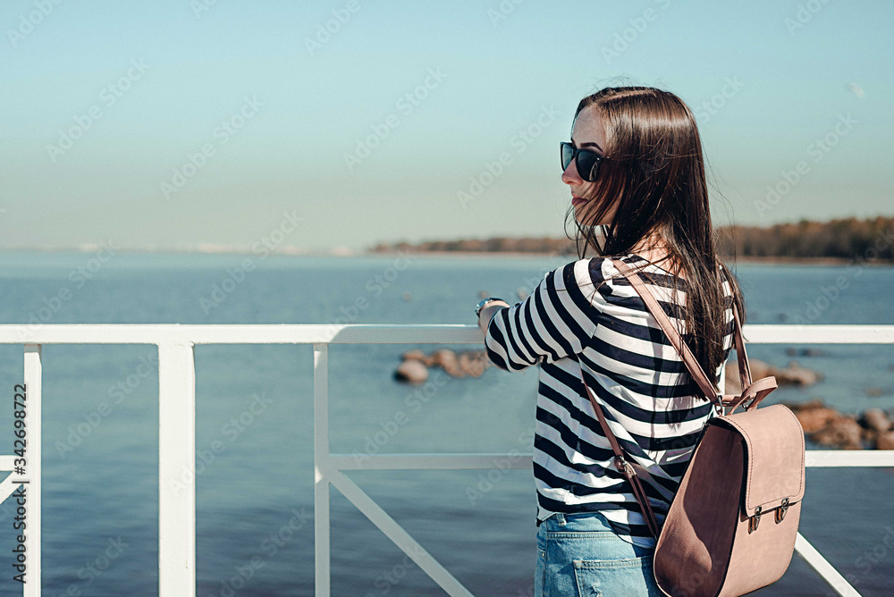 Beautiful young woman with a backpack on a background of the sea. Outdoors, lifestyle