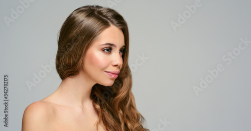 Portrait of young beautiful woman isolated at grey background. Blonde girl with long and shiny wavy hair . Smiling friendly girl with curly hairstyle