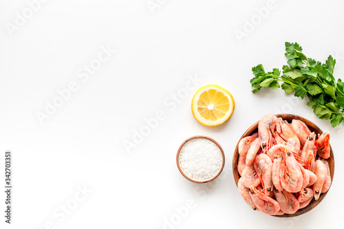 Shrimps for mediterranean salad - with lemon and greeenery - on white desk top view copy space photo
