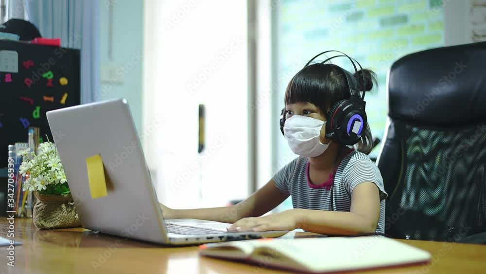 Asian child with online education. boy wear medical mask and alcohol gel studying at home, working at laptop notebook with special teacher exercise in coronavirus quarantine Asian child with online education. boy wear medical mask and alcohol gel studying at home, working at laptop notebook with special teacher exercise in coronavirus quarantine