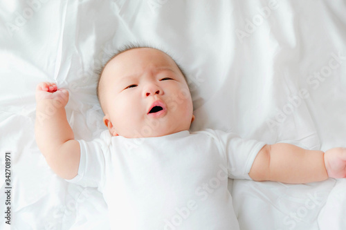 top view Portrait of a newborn Asian cute baby boy wore white Infant bodysuit on the bed , Charming Fat baby 5 month old
