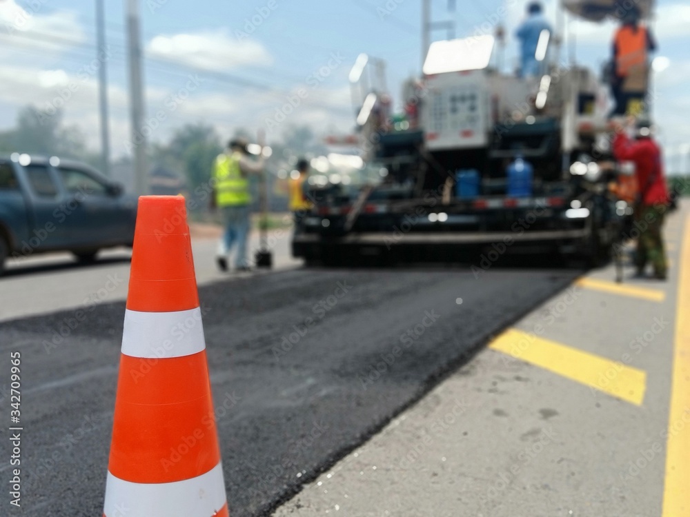 Road maintenance by the ASPHALT HOT MIX IN - PLACE RECYCLING method and with a red cone in the front (blurred image). Road maintenance by the ASPHALT HOT MIX IN - PLACE RECYCLING method and with a red cone in the front (blurred image).