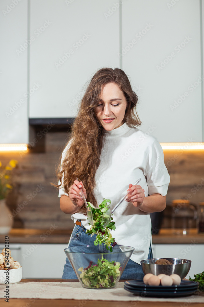 Healthy Food - Vegetable Salad. Diet. Dieting Concept. Young curly woman preparing vegetable salad in her kitchen. Healthy lifestyle concept, beautiful smiling woman mixed vegetable.