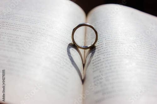 wedding ring on the background of a book with a shadow heart