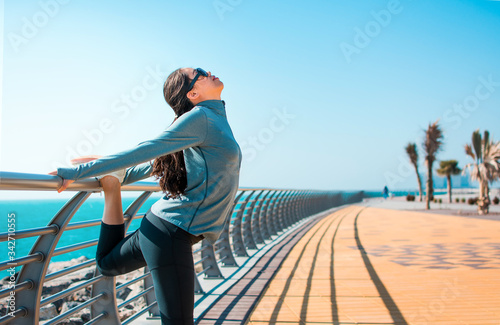 Fototapeta Naklejka Na Ścianę i Meble -  Girl stretching before workout by the seaside