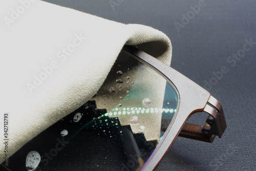 Cleaning eyeglasses with lens cleaner and wiping with micro fiber cloth