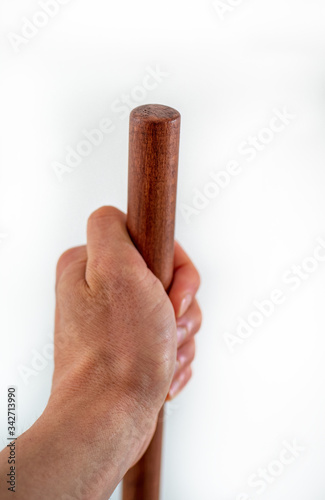 Mans hand holds brown wooden haft on white background.