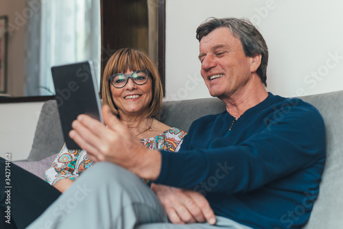 Coppia di europei di mezza età realizza una video chiamata con la famiglia. Tablet, laptop, smartphone. Distanza sociale e tecnologia 