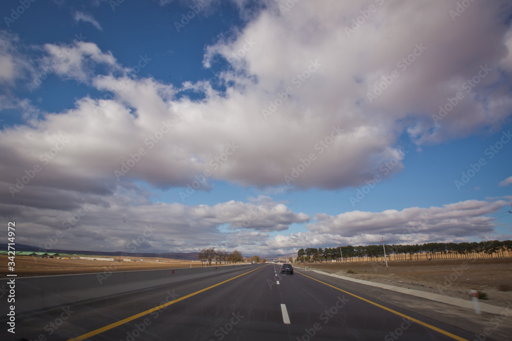 Asphalt road and bright blue sky with fluffy clouds . Empty desert asphalt road from low angle with mountains and clouds on background. road, red desert landscape . Open road with blue clouds . Asphalt road and bright blue sky with fluffy clouds . Empty desert asphalt road from low angle with mountains and clouds on background. road, red desert landscape . Open road with blue clouds .