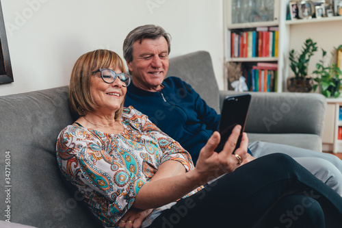 Coppia di europei di mezza età realizza una video chiamata con la famiglia. Tablet, laptop, smartphone. Distanza sociale e tecnologia 