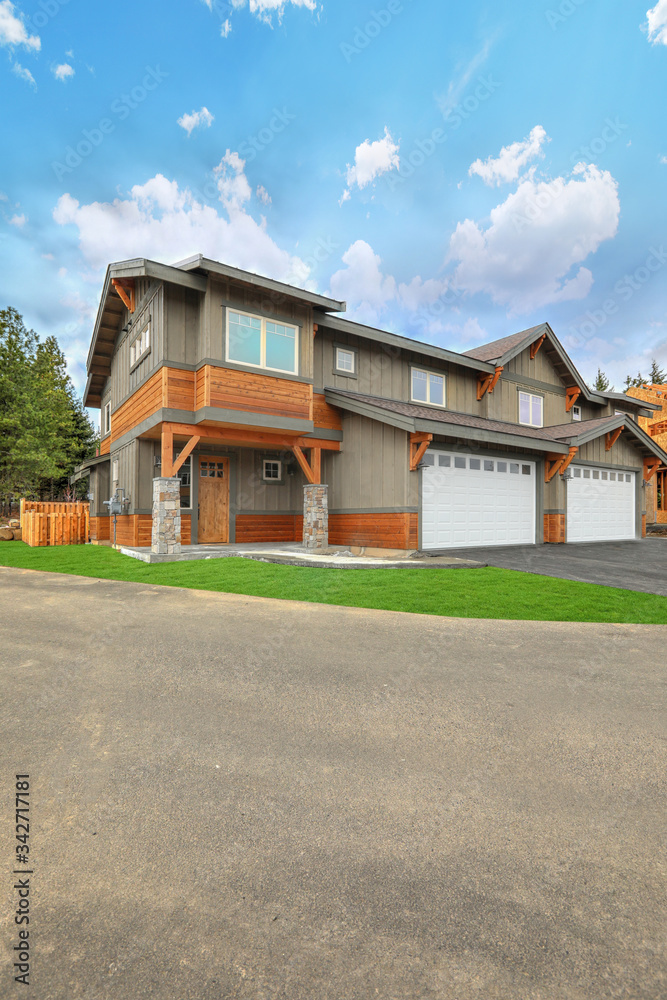 Front covered entrance to a new rustic natural townhome with concrete patio and stone columes.