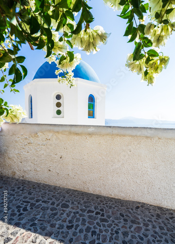 blue dome of Saint Nikolaos Peramataris orthodox church with flowers in Oia, Santorini island, Cyclades, Greece photo