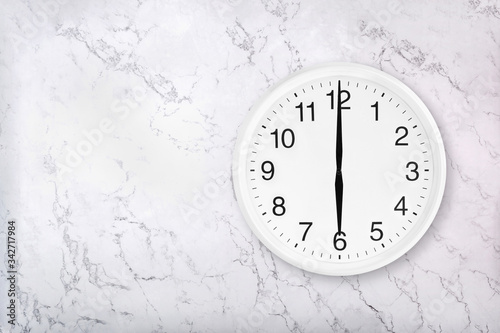 White round wall clock on white natural marble background. Six o'clock. 6 a.m. or 6 p.m