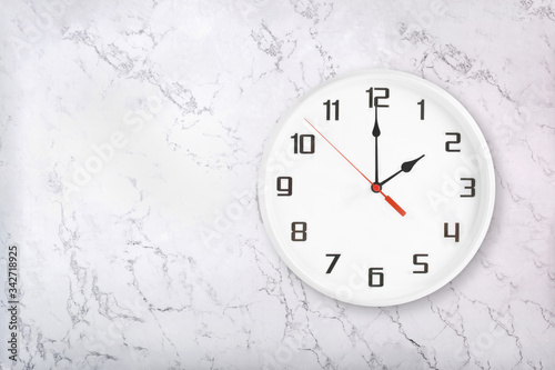 White round wall clock on white natural marble background