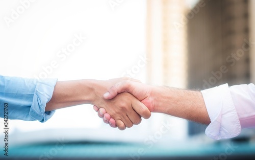 Two roll up shirt sleeves businessman shaking hands agreement with blurred building background, successful business collaboration and teamwork,Team agreement in hands gesture communication